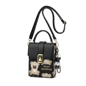 Detail of black crossbody bag featuring cartoon bear patterns and gold metal clasp