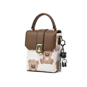 Detail of elegant gold twist lock and cute bear charm on beige mini handbag