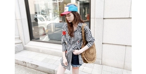 Detailed view of a round brown straw shoulder bag with a casual summer street outfit
