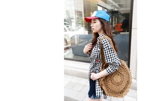 Outdoor shot of a round straw shoulder bag with wavy edges and woven texture