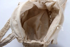 Detail view of woven beach bag showing beige fabric lining and top zipper closure