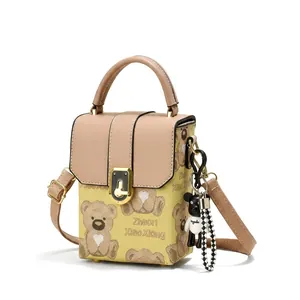 Close-up of khaki mini handbag featuring cartoon bear print and stylish metal lock detail
