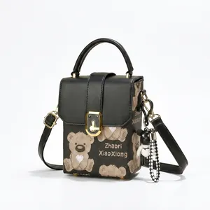 Detail view of the black crossbody bag showing the bear print and gold metal clasp