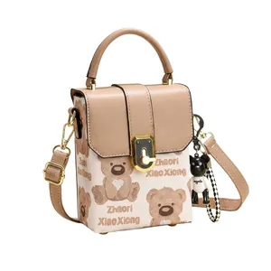 Close-up of golden rotary lock and cute bear print on a stylish milk-tea flap crossbody bag