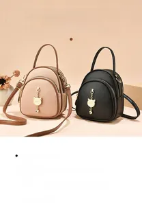 Detail view of mini multi-layer backpacks with litchi texture and golden cat charms