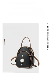 Detail showing black lychee texture leather with cute cat pendant and gold zippers