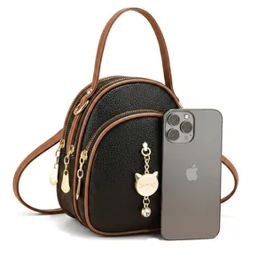 Detail view of mini black lychee leather bag with three golden zippers and cat charm
