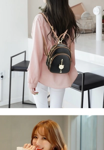 Close-up of black lychee grain mini backpack with gold cat charm and brown straps