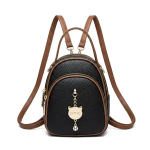 Close-up of black lychee grain leather mini backpack with gold cat charm and brown straps
