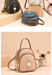 Close-up of three-layer mini backpack with gold cat pendant and lychee texture