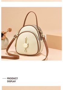 Close-up of beige lychee texture mini backpack with golden cat charm and zips