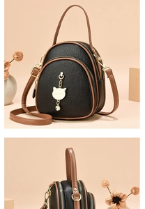 Detail of multi-layer crossbody bag with cat charm and pebbled leather texture