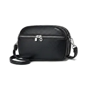 Detail view of black lychee grain leather crossbody bag with triple zipper design