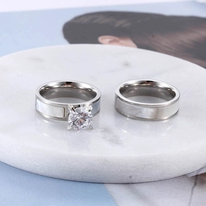 Minimalist silver titanium steel couple rings with white shell inlay on marble stand