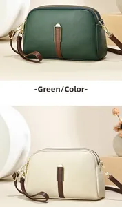 Detail of dual zipper cross-body bag in dark green and off-white litchi grain leather