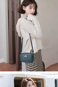 Close-up of a teal lychee grain leather mini crossbody bag with double silver zippers
