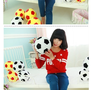 Lifestyle shot of soft plush soccer pillows in black, white, yellow and red colors