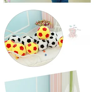 Detailed view of plush soccer pillows in classic black-white and red-yellow hex patterns