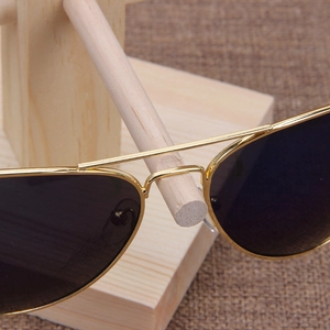 Classic gold metal aviator sunglasses with dark lenses on a wooden display stand