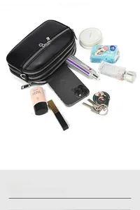 Detail of black litchi grain leather crossbody bag with triple zipper compartments