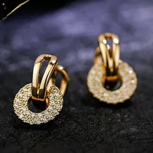 Detail of gold U-shaped earrings with a hanging ring pendant set with sparkling zircons