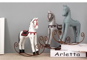 Detailed view of vintage wooden rocking horse ornaments with metallic bases on a desk