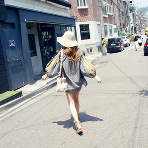 Detail shot of a handmade straw sun hat paired with a casual plaid top on a sunny street