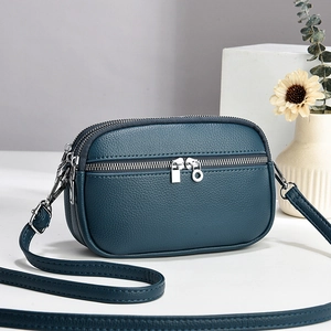Mini dark teal pebble leather crossbody bag with triple zipper and slim shoulder strap