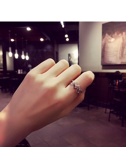 Detailed view of silver wave ring with pavé-set crystals worn on a finger