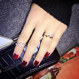 Detailed view of layered rose gold rings with crisscross zircon and wave designs