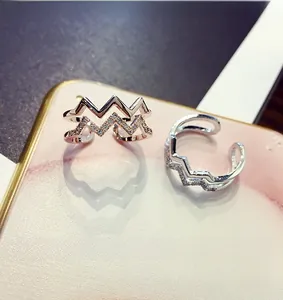 Close-up of double-layer wave rings in silver and rose gold with zircon crystals