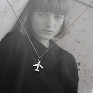 Macro shot of S925 hallmark on minimalist silver airplane pendant and fine chain