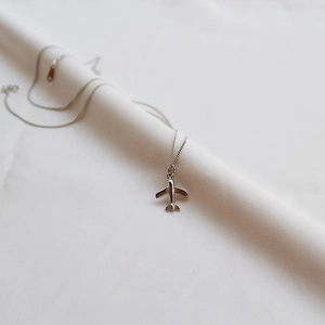 Close-up of a 925 silver airplane pendant on silk background showing high-polish finish