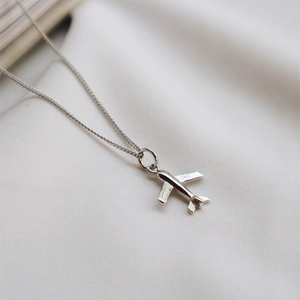 Macro shot of 925 sterling silver airplane pendant with polished mirror finish details