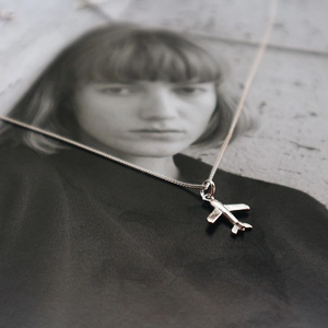 Detail of 925 sterling silver airplane pendant necklace over blurred portrait background