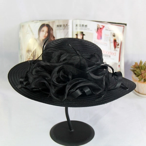 Detail of black wide-brim organza sun hat with layered floral accents on display stand