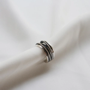Detailed view of vintage S925 sterling silver ring with braided texture on white fabric