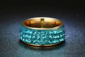 Detailed view of golden stainless steel ring with three rows of blue crystals