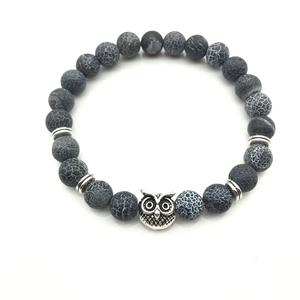 Close-up of weathered agate beads and owl charm on a bohemian style stretch bracelet