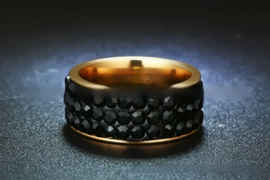 Detailed close-up of wide gold-plated stainless steel ring featuring black crystal beads