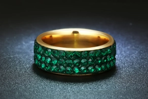 Detailed close-up of a gold-plated stainless steel ring featuring three rows of green crystals