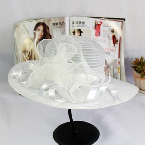 Detail of white organza sun hat with large floral ribbon and wave-edged brim