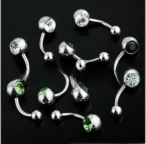 Detail of assorted stainless steel belly rings with colored rhinestones on black background