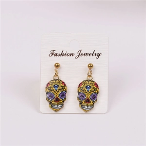Detail of colorful enamel skull earrings with gold hardware on a display card