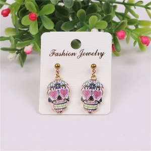 Detailed close-up of pink skull drop earrings with purple hearts and gold plating