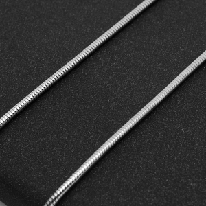 Macro shot of silver stainless steel snake chain with smooth texture on black background