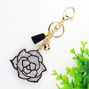 Detailed view of camellia flower keychain with white rhinestones and black fringe tassel