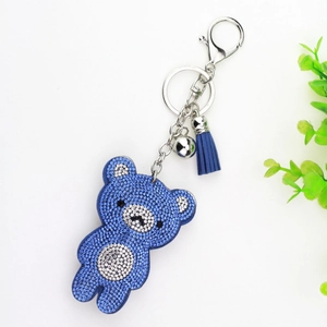 Detail of blue rhinestone bear keychain with silver ring, bell and leather tassel