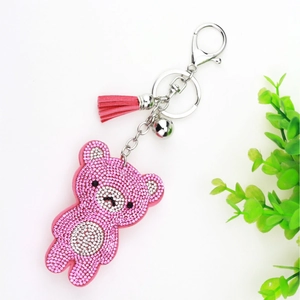 Pink rhinestone bear keychain with tassels and bell on a clean white background