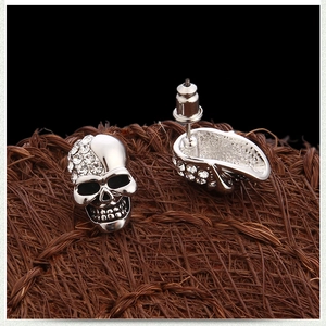 Macro shot of silver skull stud earrings with sparkling crystals and metal details